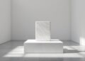 Minimalist white gallery with a marble pedestal and a smaller marble block on top, bathed in sunlight.