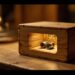 Wooden rectangular box with a carved window showing two small metal gears inside, lit warmly.