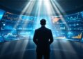 A person in a dark suit stands with back to the camera, facing a curved wall of glowing data dashboards and charts.