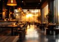 Restaurant dining area bathed in golden sunset light, with warm pendant lamps and candles on tables.